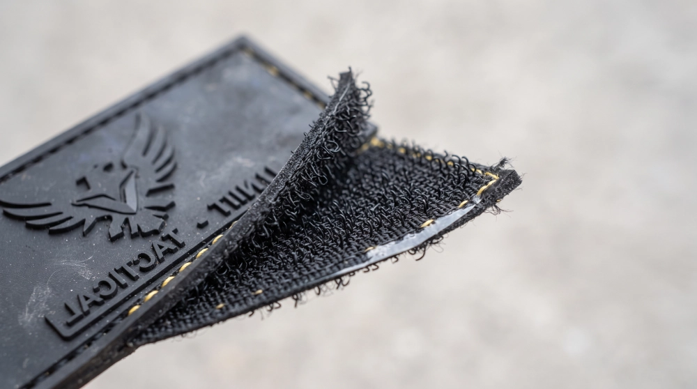 Close-up of a PVC patch's hook-and-loop Velcro backing peeled back to show the fabric hook material